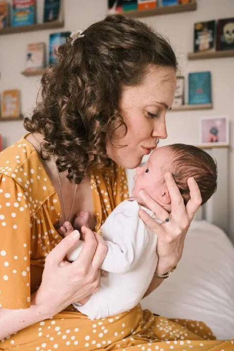 Mother gently kissing her newborn during an at home session in Newcastle