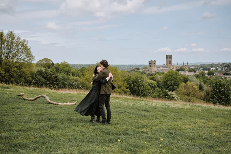 The newly engaged couple embracing with Durham Cathedral behind them
